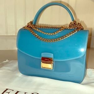 A blue Furla jelly crossbody with gold chain.